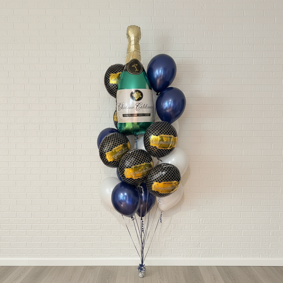 Bouquet of balloons shaped like a bottle of champagne against a white brick wall.